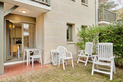 a group of white chairs and tables on a patio at Citea Deauville - Tourisme & Vacances mer in Deauville