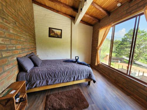een slaapkamer met een bed en een groot raam bij Hotel Pueblo del mundo in Baños