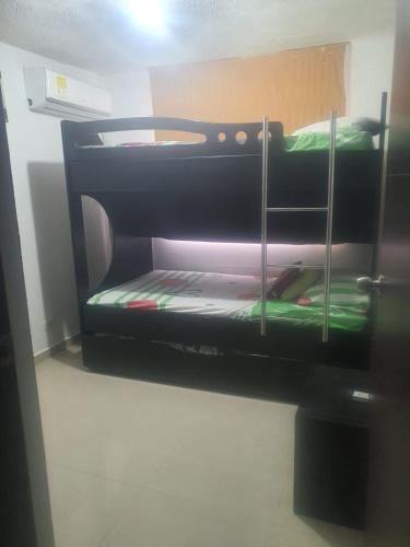 a bunk bed in a room with green sheets at Apto Torres de Montreal in Barranquilla