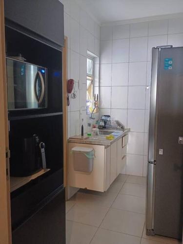 a kitchen with a sink and a refrigerator at Quarto Cambuí l Apto compartilhado in Campinas