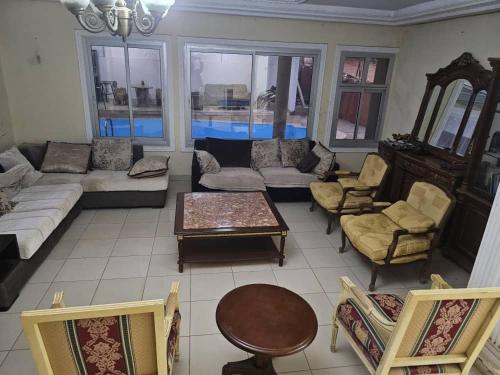 een woonkamer met een bank en een tafel en stoelen bij Résidence Élisabeth in Fondjomékwet