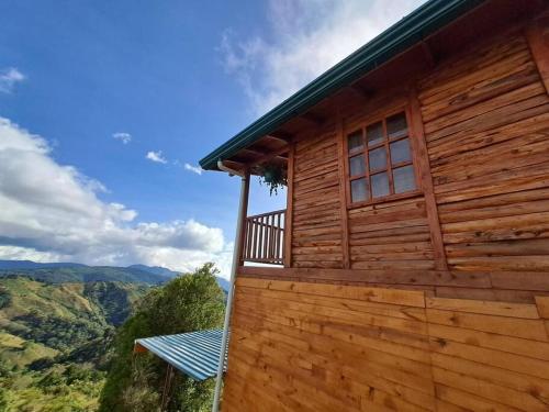 a wooden house with a balcony on the side of it at Cabaña Cebra - THE Spot for GREAT Sunset views! in Jardín