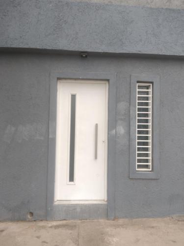 a white door and a window in a gray building at Dpto Lgolf club cerca de Estadio único in Santiago del Estero