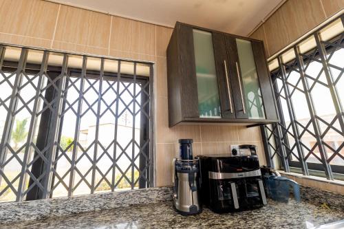 a kitchen with a coffee maker on a counter with windows at HomeAwayFromHome Villa in Lapaz