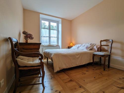 une chambre avec un lit et deux chaises et une fenêtre dans l'établissement Appartement XIXe siècle - Centre-ville du Puy-en-Velay, 2 chambres, tout confort, proche monuments - FR-1-582-6, au Puy-en-Velay