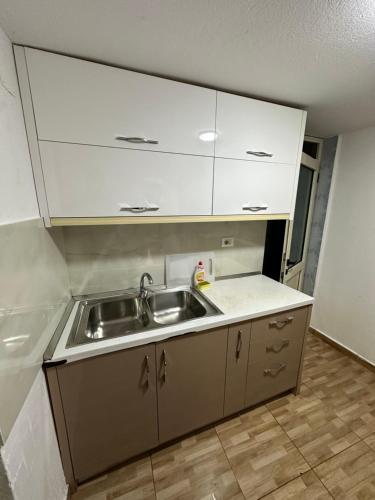 a kitchen with a sink and white cabinets at Elby Apartments in Berat