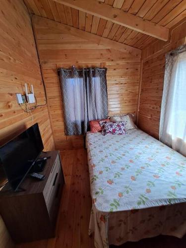 a bedroom with a bed and a television in a cabin at Cabaña Gitana - Magical and WINDY nature getaway! in Jardín