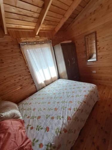 a bed in a wooden room with a window at Cabaña Gitana - Magical and WINDY nature getaway! in Jardín