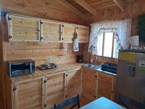 a kitchen with wooden cabinets and a sink in a cabin at Cabaña Gitana - Magical and WINDY nature getaway! in Jardín