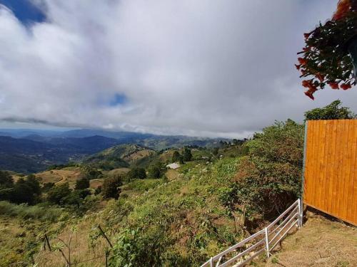 a view of a hill with a fence and mountains at Cabaña Gitana - Magical and WINDY nature getaway! in Jardín