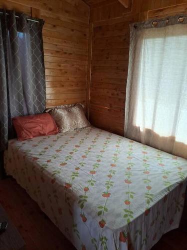 a bed in a wooden room with a window at Cabaña Gitana - Magical and WINDY nature getaway! in Jardín