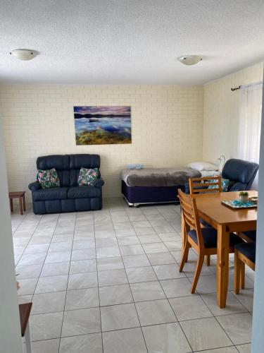 ein Wohnzimmer mit einem Sofa, einem Bett und einem Tisch in der Unterkunft Marcel Towers Holiday Apartments in Nambucca Heads
