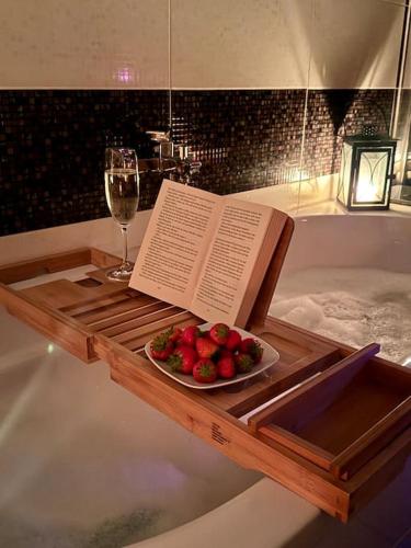 a table with a book and a bowl of strawberries and a glass of wine at Schick, gemütlich & Nähe Therme in Bad Lippspringe