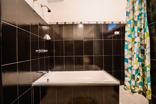 uma banheira na casa de banho com azulejos pretos em Blue Lotus Retreat Center em Písac