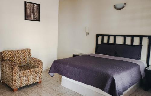 a bedroom with a bed and a chair at Hotel Paraiso in Puerto Peñasco