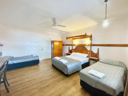 um quarto com 2 camas, uma secretária e uma mesa em Yongala Lodge by The Strand em Townsville