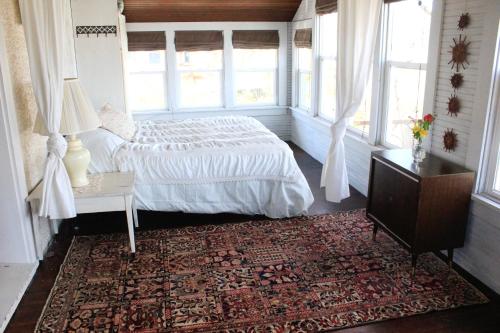 een slaapkamer met een bed en een tafel en ramen bij Garden Guesthouse in Viroqua