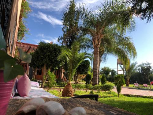 une table avec des palmiers devant un bâtiment dans l'établissement Teacook Marrakech, à Ouled el guerne