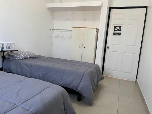 a bedroom with two beds and a white door at Habitaciones en Casa Casiopea in Tijuana