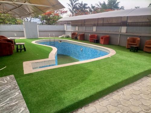 a swimming pool with green grass next to a building at Executive Gold Hotel in Abuja
