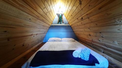 a bed in a room with a wooden wall at NOMADAS chales, mini casinhas, bangalôs e area de camping in Bonito