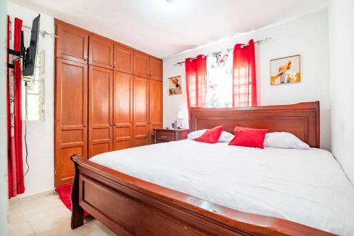 een slaapkamer met een groot bed met rode gordijnen bij Hermosos apartamentos a 5 mins de la playa Caleta in La Romana