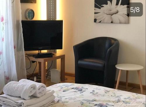 ein Schlafzimmer mit einem Bett, einem Stuhl und einem TV in der Unterkunft City Center in Basel