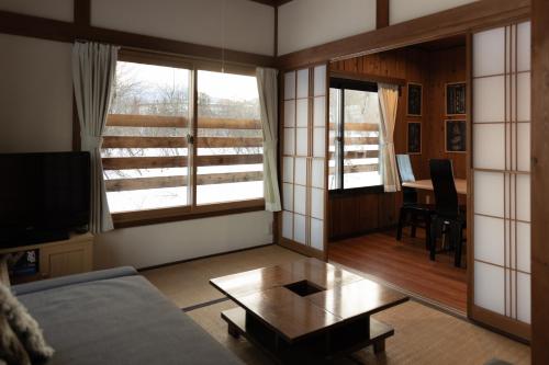 a living room with a couch and a table at Lucky Duck Cabin Myoko in Myoko