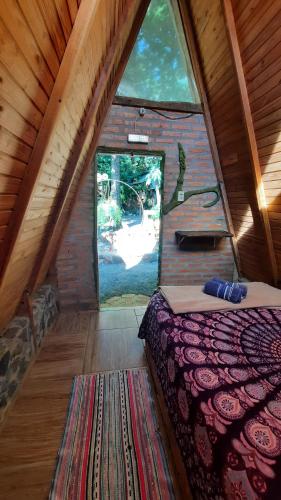 a bed in a room with a large window at NOMADAS chales, mini casinhas, bangalôs e area de camping in Bonito