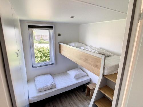 Cette petite chambre comprend des lits superposés et une fenêtre. dans l'établissement Mobil-home 6 pers, 3 chambres, piscine chauffée, plage à 200m, terrasse couverte - FR-1-361A-12, à Jullouville