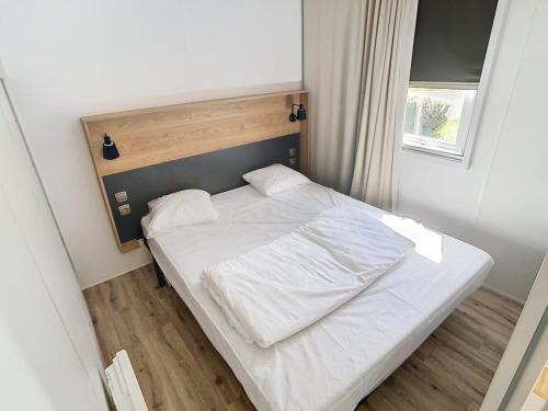 een bed met witte lakens en kussens in een slaapkamer bij Mobil-Home Jullouville, 3 pièces, 4 personnes - FR-1-361A-15 in Jullouville-les-Pins