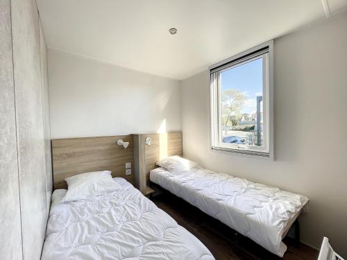 2 camas en una habitación con ventana en Mobil-Home Jullouville, 4 pièces, 6 personnes - FR-1-361A-16, en Jullouville-les-Pins