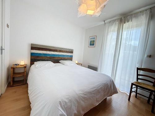 une chambre avec un grand lit blanc et une fenêtre dans l'établissement Charmant T2 avec double terrasse près de la plage - Donville-les-Bains - FR-1-361-442, à Donville-les-Bains