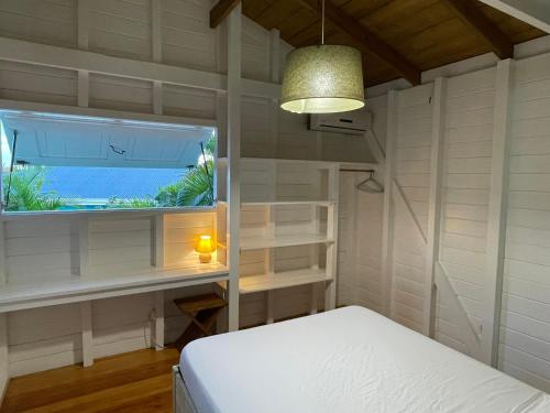 a bedroom with a bed and a large window at Charmant bungalow avec petite piscine privée in Rivière-Salée