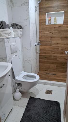 une salle de bain blanche avec toilettes et douche dans l'établissement Apartman Dzejda, à Novi Pazar