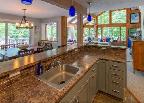 a kitchen with a sink and a living room at Loon Mtn Pool Hot Tub Firepit Sleeps 17 in Lincoln