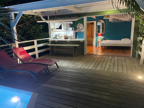 a deck with two chairs and a table and a bed at Charmant bungalow avec petite piscine privée in Rivière-Salée