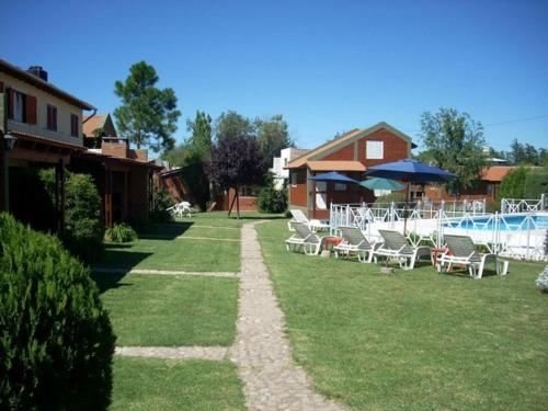 a yard with chairs and a pool and a house at Complejo Cantonavi in Mina Clavero