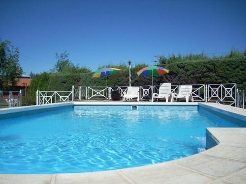 a swimming pool with two chairs and two umbrellas at Complejo Cantonavi in Mina Clavero