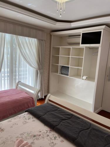 1 dormitorio con 1 cama, TV y ventana en Casa da Fabi, en Gramado