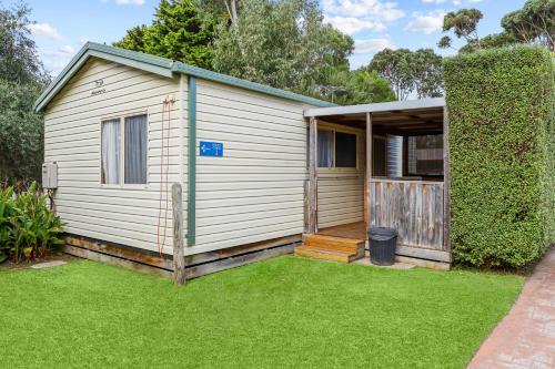 a small white shed with a grass yard at Anchor Belle Holiday Park in Cowes