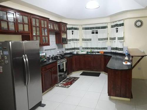 a kitchen with wooden cabinets and a stainless steel refrigerator at The Essence of Quiet and Comfort in Roseau