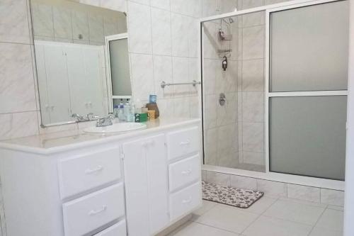 a white bathroom with a sink and a shower at The Essence of Quiet and Comfort in Roseau