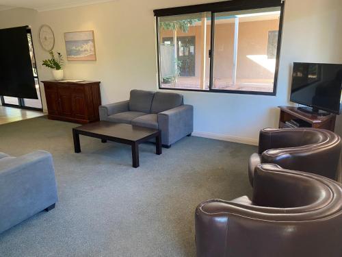 a living room with couches chairs and a tv at Ningaloo Breeze Villa 3 in Exmouth