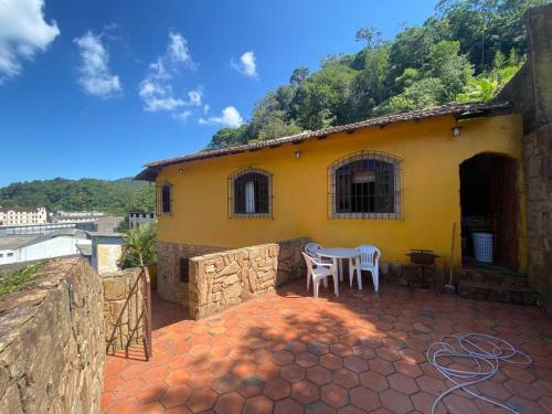 a yellow house with a table and chairs on a patio at Casa 86 Quitandinha Petrópolis in Petrópolis