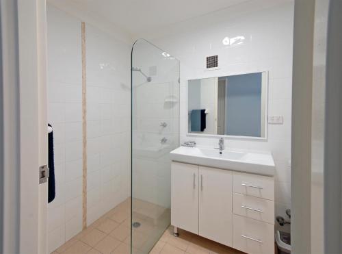 a white bathroom with a sink and a shower at Marcel Towers Holiday Apartments in Nambucca Heads