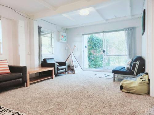 ein Wohnzimmer mit Möbeln und einem großen Fenster in der Unterkunft Sunny Cosy stay in Auckland in Auckland