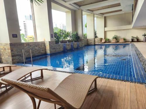 een groot zwembad met stoelen in een gebouw bij Cosy KL Tower with Parkview Balcony, Pool, Gym, Sauna Near Greenbelt 100MBPS in Manilla