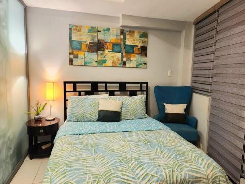 een slaapkamer met een bed en een blauwe stoel bij Cosy KL Tower with Parkview Balcony, Pool, Gym, Sauna Near Greenbelt 100MBPS in Manilla