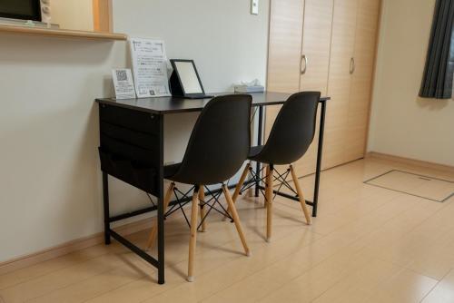 a desk with three chairs sitting next to a desk at apartment hotel myu in Mito